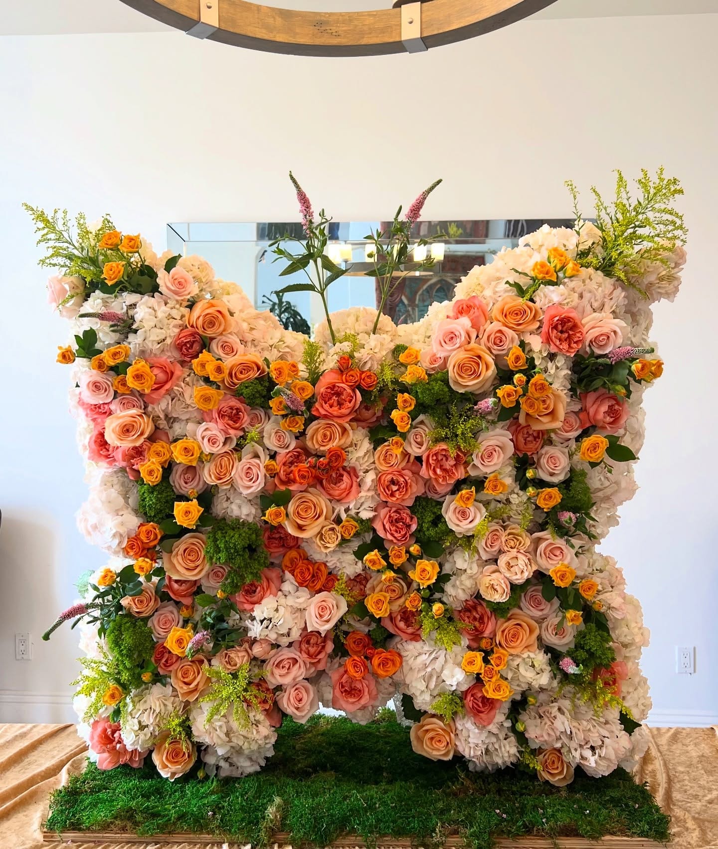 Life-size butterfly-shaped floral wall of white, blush, peach and coral roses and hydrangea